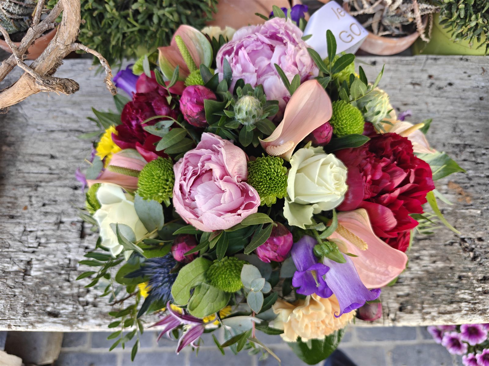 Een boeket met pioenrozen, calla’s, witte rozen en groene chrysanten