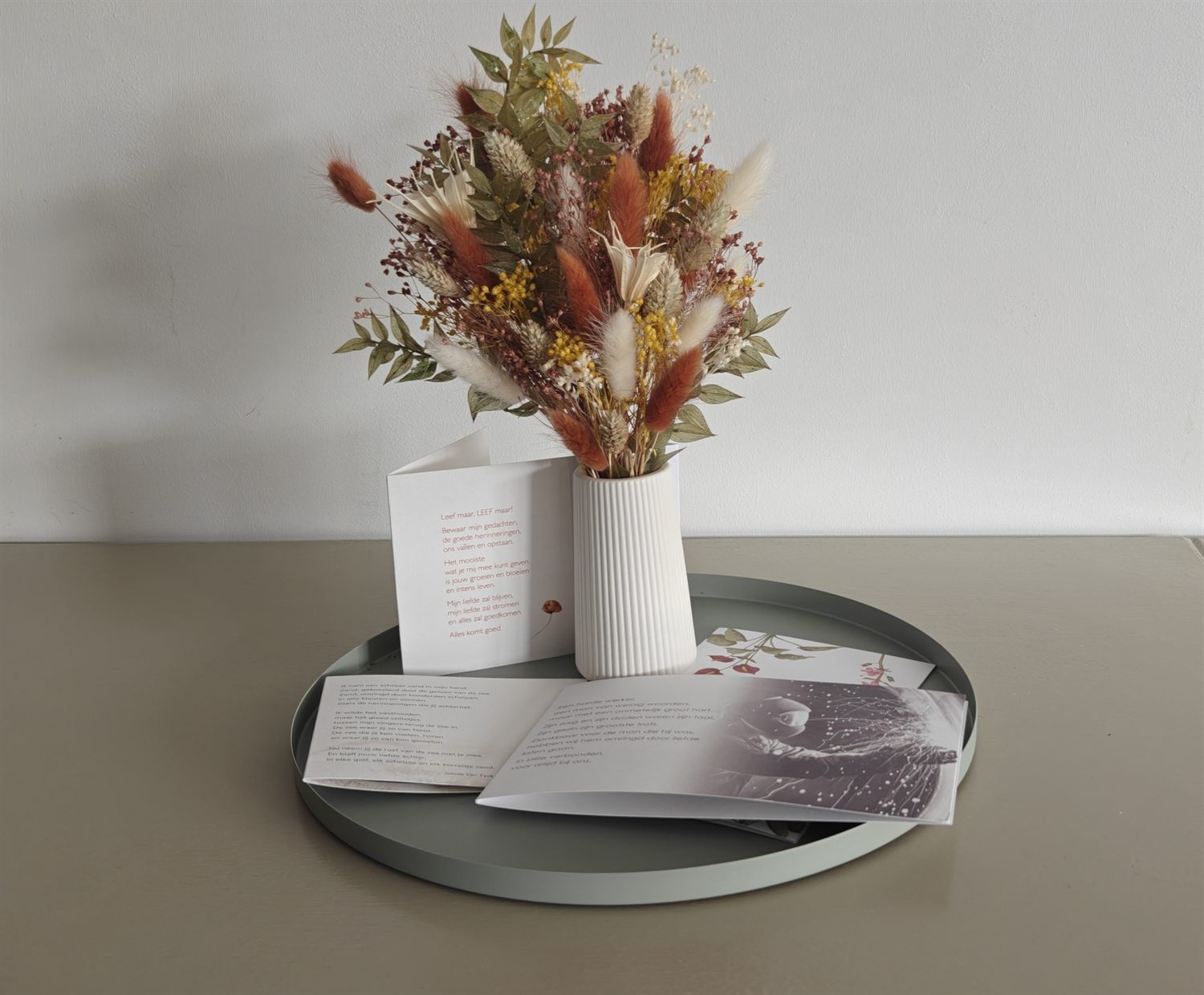 Herinneringskaarten met rouwteksten op een schaal, bij een boeket droogbloemen